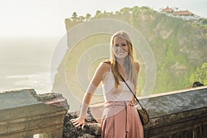 Young woman traveler in Pura Luhur Uluwatu temple, Bali, Indonesia. Amazing landscape - cliff with blue sky and sea