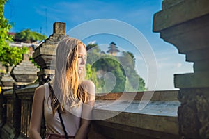 Young woman traveler in Pura Luhur Uluwatu temple, Bali, Indonesia. Amazing landscape - cliff with blue sky and sea