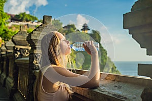 Young woman traveler in Pura Luhur Uluwatu temple, Bali, Indonesia. Amazing landscape - cliff with blue sky and sea