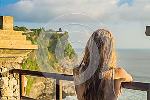 Young woman traveler in Pura Luhur Uluwatu temple, Bali, Indonesia. Amazing landscape - cliff with blue sky and sea