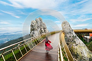 Young woman traveler in red dress enjoying at Golden Bridge in Bana hills, Danang Vietnam, Travel lifestyle