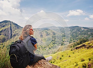 Young woman traveler sits overlooking a beautiful mountain landscape