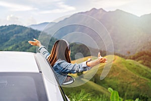 Young woman traveler sitting in a car watching a beautiful mountain view while travel driving road trip