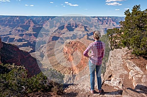 Young woman traveler standing at the edge of the cliff and admire the Grand Canyon National Park in Arizona USA