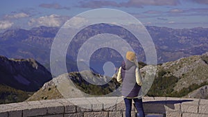 A young woman traveler visits the view point on the top of the Lovcen mountain. The Mausoleum of Petar II Petrovic