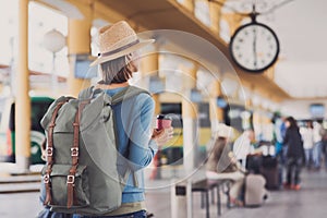 Young woman traveler waiting for a bus on a bus station, travel and active lifestyle concept