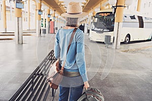 Young woman traveler waiting for a bus on a bus station, travel and active lifestyle concept