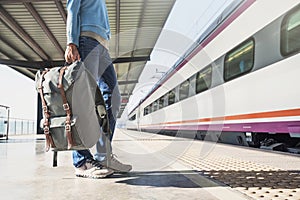 Young woman traveler waiting for a train on a railroad station, travel and active lifestyle concept