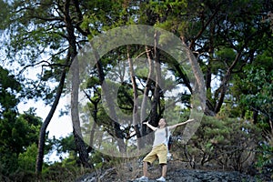 Young woman traveler walking in the forest and enjoying for beautiful view of nature on holiday.Adventure concept with hands up