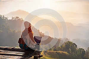 Young woman traveler working online using laptop and enjoying the beautiful nature landscape with mountain view