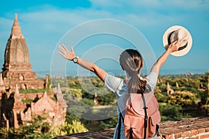 Young woman traveling backpacker with hat, Asian traveler standing on Pagoda and looking Beautiful ancient temples