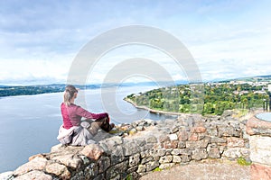 Young woman traveller sitting on top mountain contemplating spec