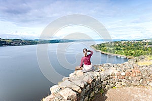 Young woman traveller sitting on top mountain contemplating spec