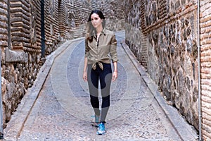 Young woman traveller walking through a narrow street during a antumn afternoon looking to the camera