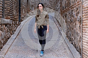 Young woman traveller walking through a narrow street during a antumn afternoon looking to the camera