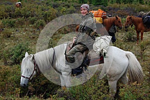 Young woman travels through the moutnains on horseback. photo