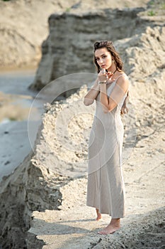 Young woman in a trendy summer linen dress posing on the beach by the sea