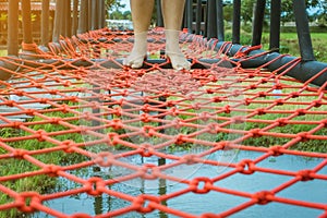 Young woman tried to walk on the bridge floor tied with a red rope to cross the swamp in the fields.