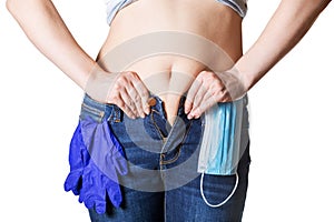 Young woman tries to button her jeans after quarantine. Concept of unhealthy lifestyle and overeating during self-isolation.