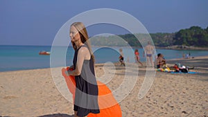 Young woman on a tropical beach inflate an inflatable sofa. Summer vacation concept