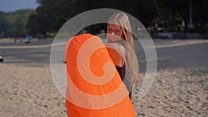 Young woman on a tropical beach inflate an inflatable sofa. Summer vacation concept