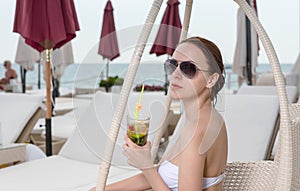 Young Woman with Tropical Drink on Resort Patio