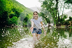 The young woman at a tropical river playful, the splashing of water. Skincare spa treatment concept. Summer vacation. Healthy