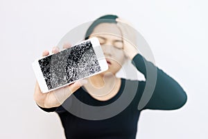 Young woman with troubled expression holding her broken phone