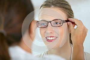 Young woman trying on eyeglasses at optical store photo