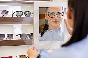 Young woman trying glasses at optic store