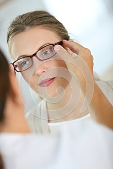 Young woman trying on new eyeglasses