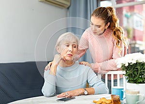 Young woman trying to apologize to offended mother at home