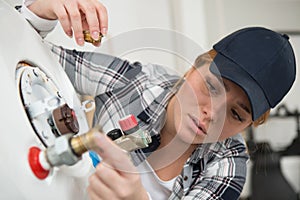 Young woman trying to fix boiler