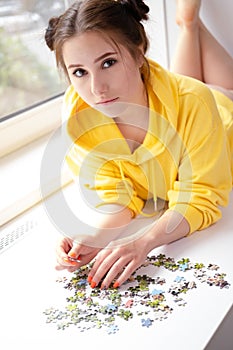 Young Woman trying to match pieces of a Jigsaw Puzzle Game. Playing board game.