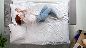 young woman trying to relax due to a nervous breakdown on the bed in bedroom, top view