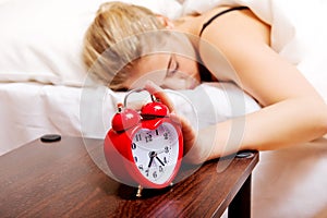 Young woman trying to sleep when alarm clock ringing