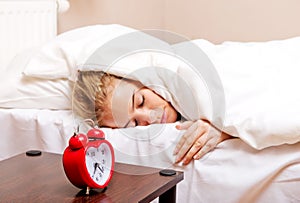 Young woman trying to sleep when alarm clock ringing