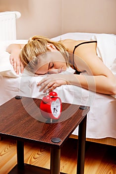 Young woman trying to sleep when alarm clock ringing