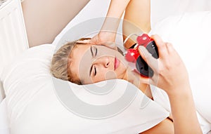 Young woman trying to sleep when alarm clock ringing