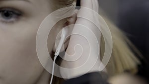 Young woman tucks hair behind ear. Action. Attractive young woman tucks her hair behind her ear with earpiece. Modern