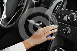 Young woman tuning radio in car, closeup