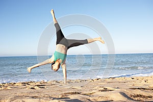 Young Woman Turning Cartwheel On Beach photo