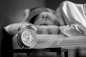 Young woman turning off alarm clock in morning late without looking clock. Relaxation and people lifestyles of tired worker