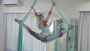 Young woman turns around in fabric hammock indoors.