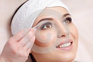 Young woman tweezing her eyebrows in beauty saloon