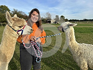 Young woman with two alpacas, a Huacaya and a Suri, outdoors