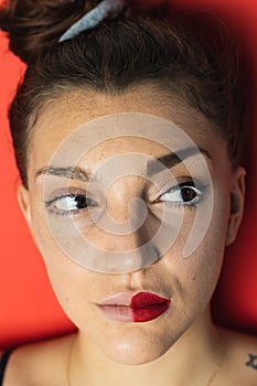 Young woman with two different lipsticks. Red background