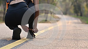 Young woman tying shoe laces getting ready for jogging at the park.