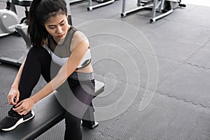 young woman tying shoelace in fitness center. female athlete prepare for training in gym. sporty girl lacing her shoes before