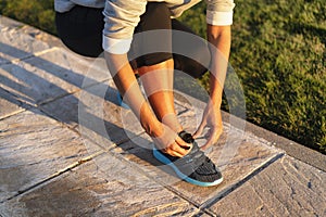 Young woman tying shoelace of sneakers to make outwork training running. Fitness and healthy lifestyle photo